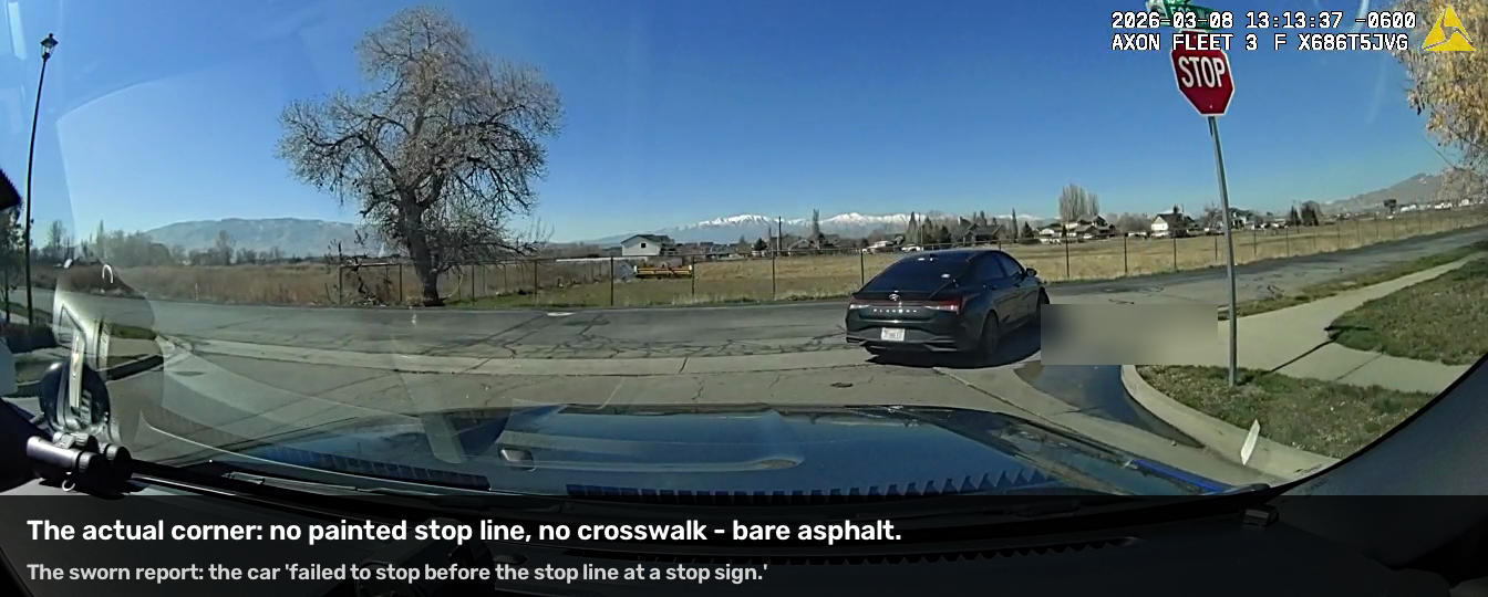 The intersection pavement from the dash camera&rsquo;s close pass: bare asphalt, no painted stop line or crosswalk.