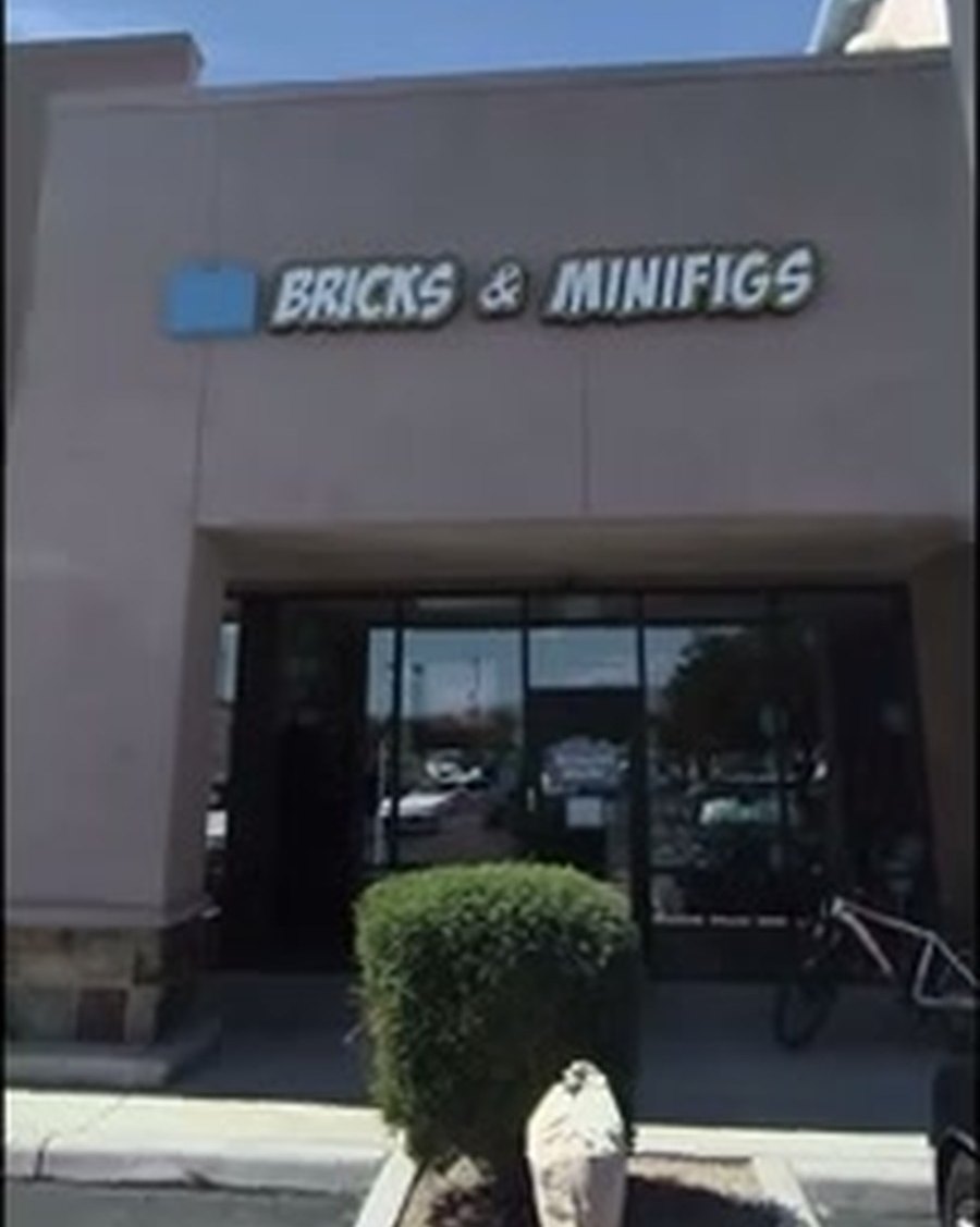 The storefront at 8110 S Houghton Rd on September 17, 2026. The channel-letter sign above the entrance reads BRICKS AND MINIFIGS with the brand's brick logo. The entrance below is dark.